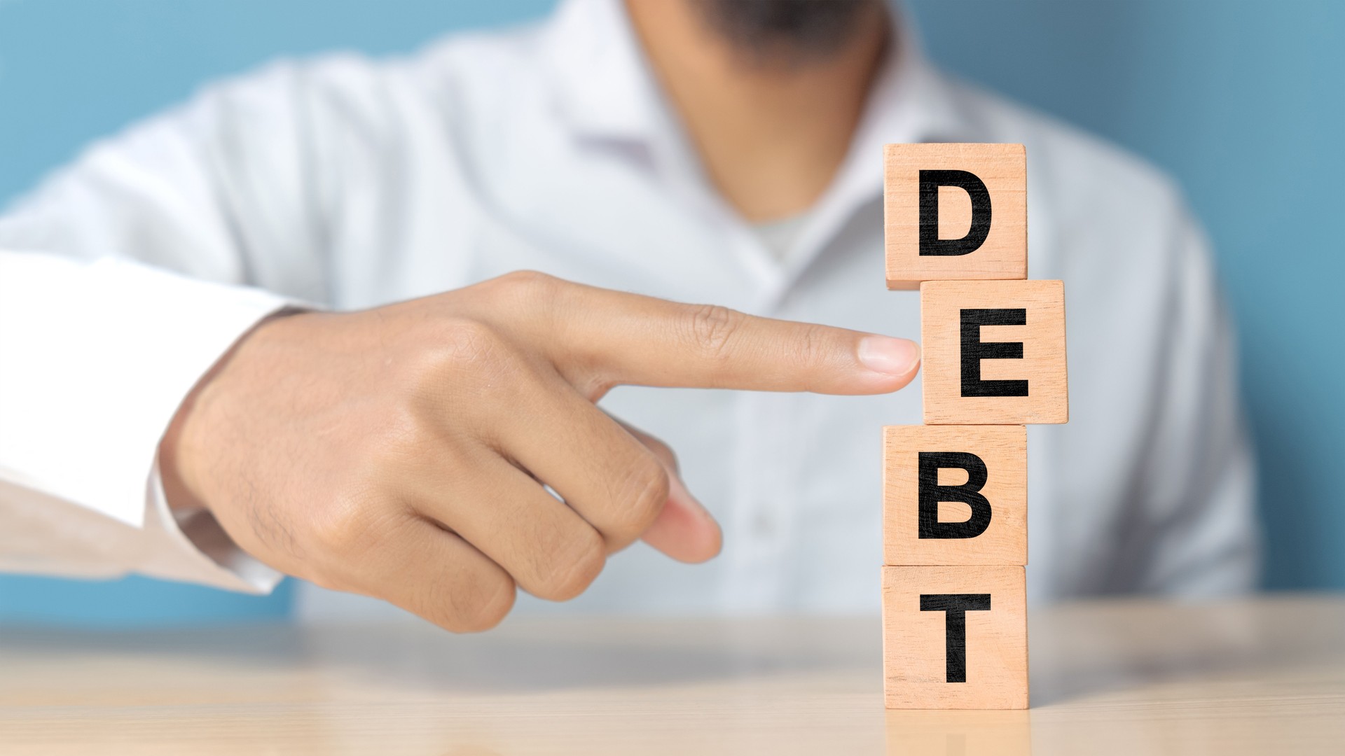 Businessman removes wooden blocks with the word Debt. Reduction or restructuring of debt. Bankruptcy announcement. Refusal to pay debts or loans and invalidate them